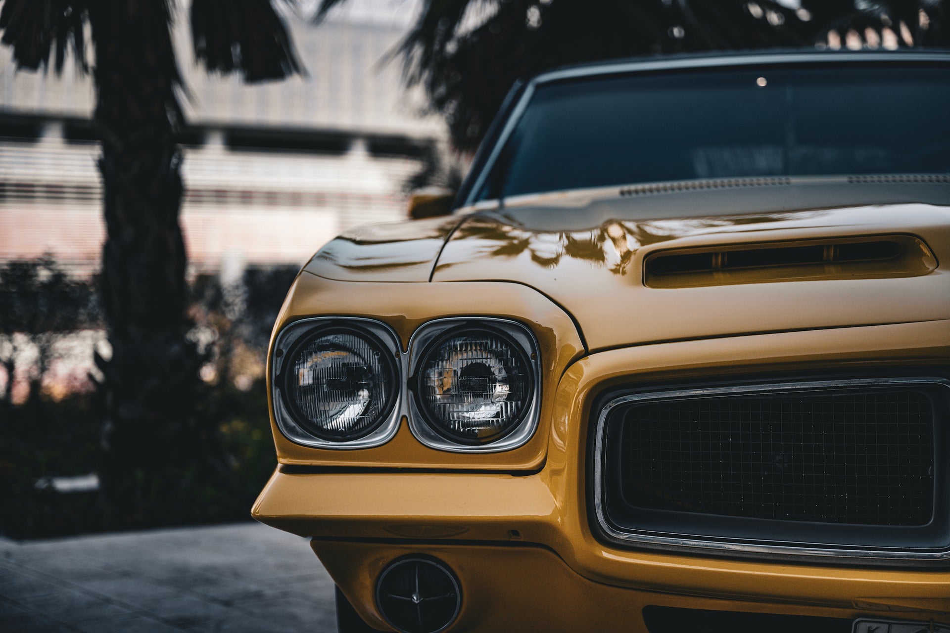 Vintage yellow car on display at Monterey Car Week, featuring distinctive dual headlights and a sleek, reflective chrome grille set.