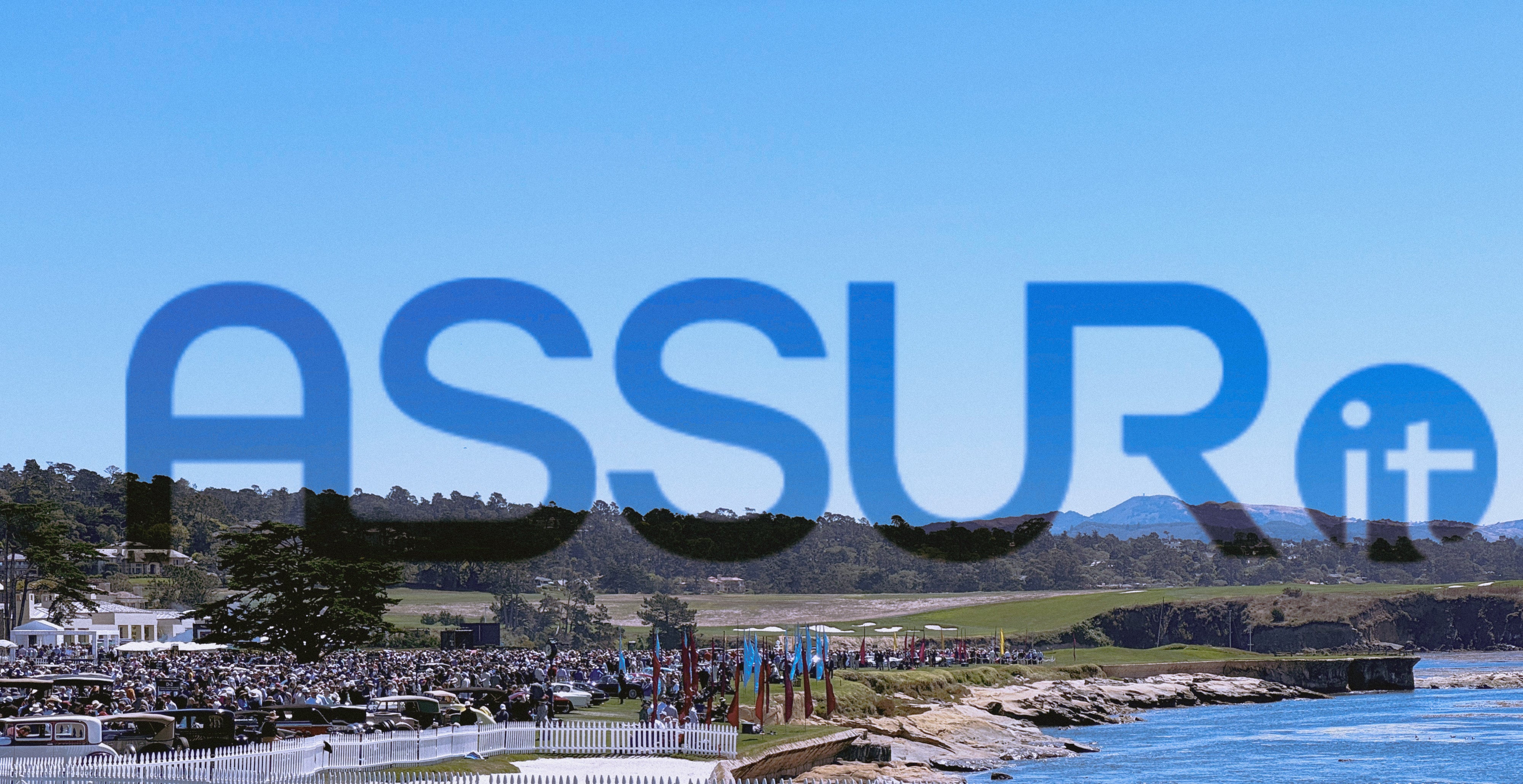 The image shows a scenic view of Monterey Car Week 2024 with a large crowd gathered near the coastline, overlaid by the ASSURIoT logo. The blue sky and ocean are prominent in the background.